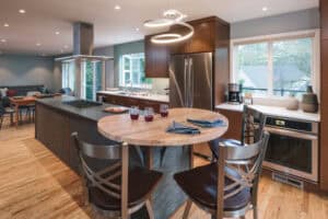 Kitchen with a central island and a round countertop at the end with two bar stool chairs.