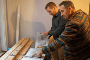 Neil Kelly carpenters looking at a project floorplan.